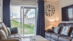 Un salon avec un canapé, une table basse, un téléviseur et une grande horloge murale.