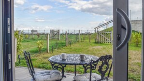 Une terrasse extérieure avec une table ronde et des chaises, un portail et une vue sur un champ verdoyant.