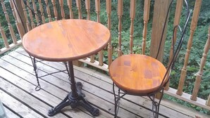 A wooden deck with two round tables and chairs, surrounded by a wooden railing with a view of greenery. - Whee House (Cullowhee)
