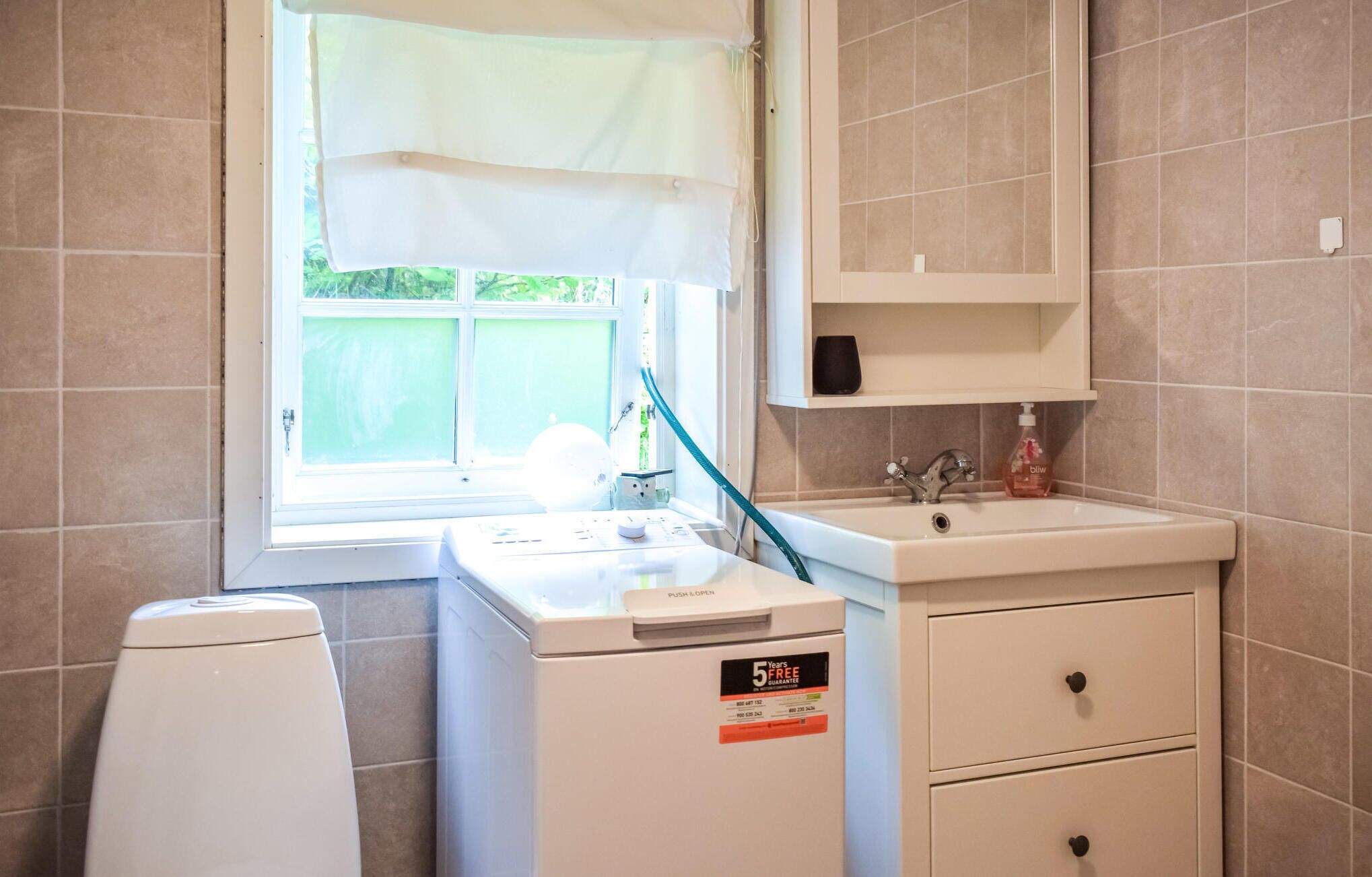 Un bany compacte amb rentadora, un lavabo i un armari.