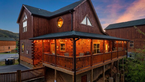 Une grande cabane en rondins dotée d’un balcon et de nombreuses fenêtres.