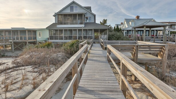 A wooden boardwalk leading to a beachfront house with a balcony, surrounded by sand and sparse vegetation. - High Tide - Beachfront Home in "Arrogantly Shabby" Pawleys Island, SC (Pawleys Island)