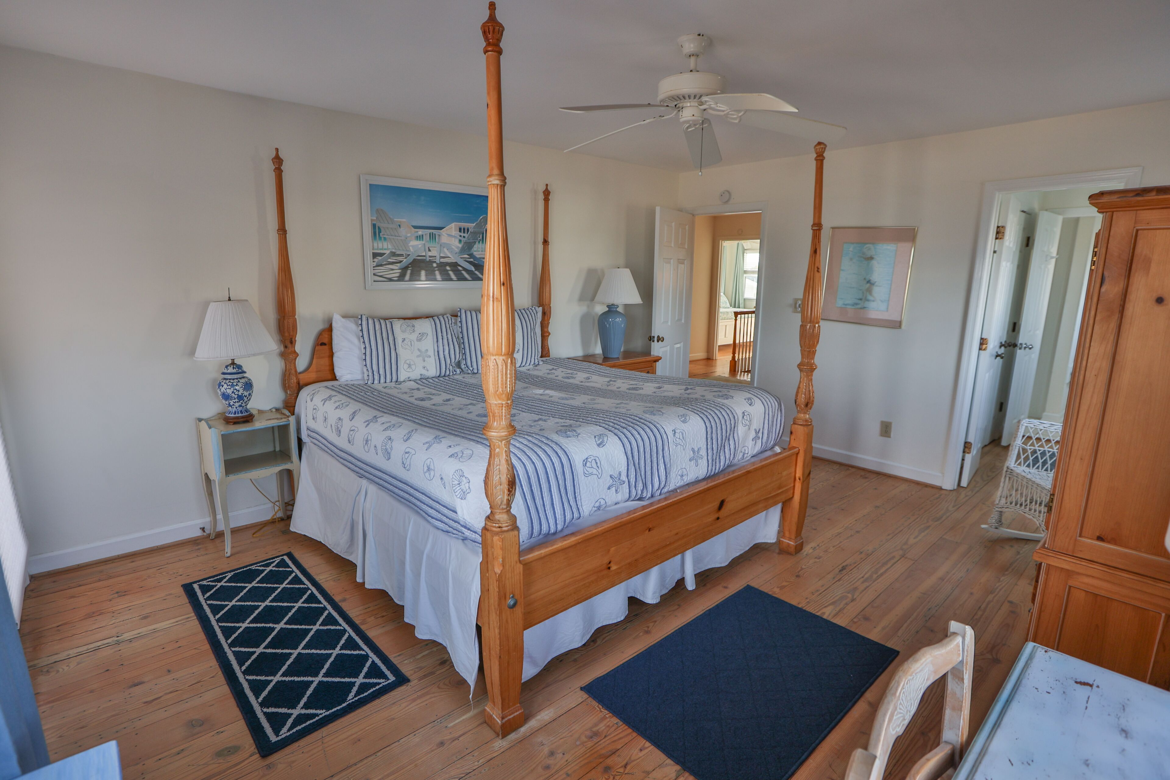 A four-poster bed with a wooden frame, a ceiling fan, and a nightstand with a lamp.