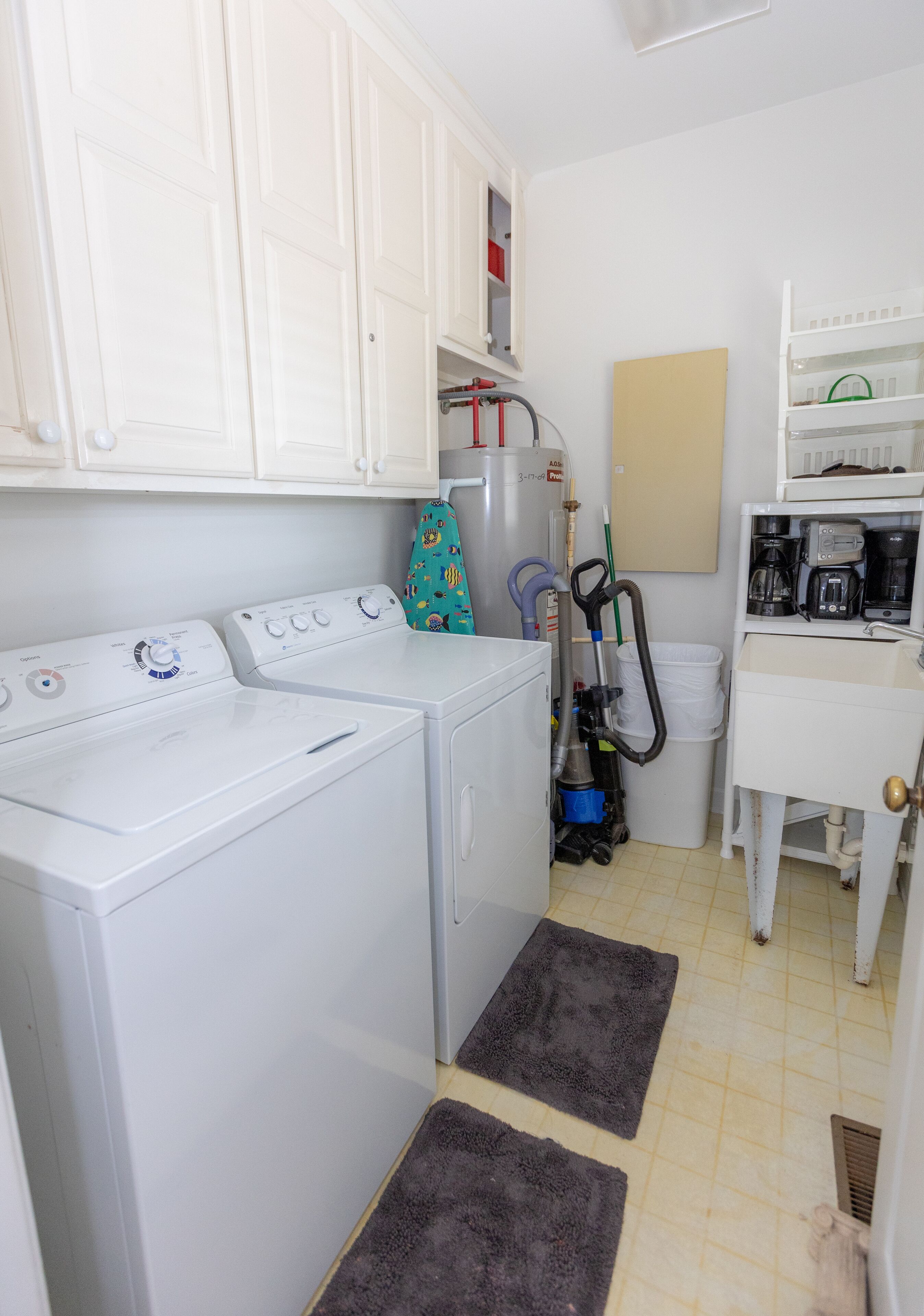 A laundry room with two washing machines, a drying rack, and a coffee maker.