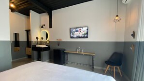 A modern hotel room with a large bed, a vanity with a mirror, a small desk, and a television on the wall. - Hotel NEXT Guadalajara (Zapopan)