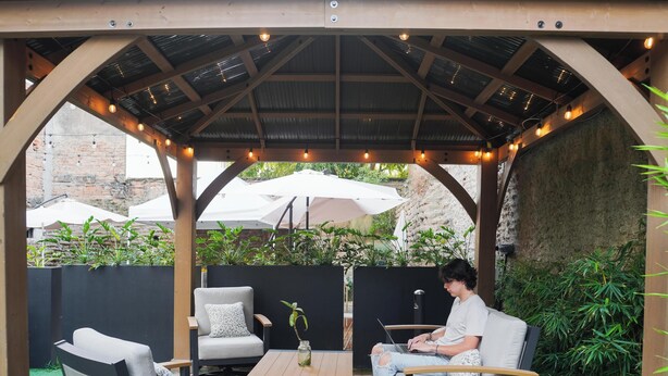 A covered outdoor seating area with chairs, a table, and string lights. - Hotel NEXT Guadalajara (Zapopan)