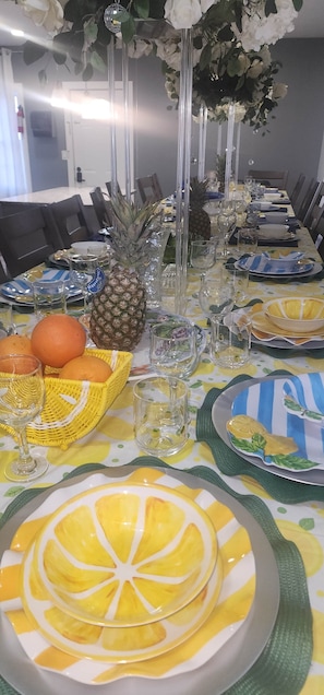 A dining table set with plates, glasses, and a pineapple centerpiece.