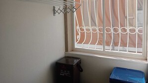 Un espace dédié à la lessive, équipé d’un étendoir, d’un bac de compost noir et d’un bac de rangement bleu.