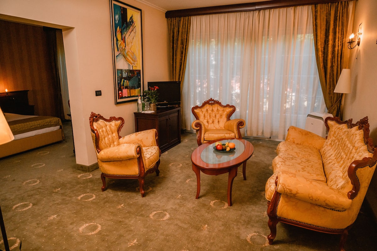 Un salon comprenant deux fauteuils, un canapé, une table basse, un téléviseur et un tableau accroché au mur.
