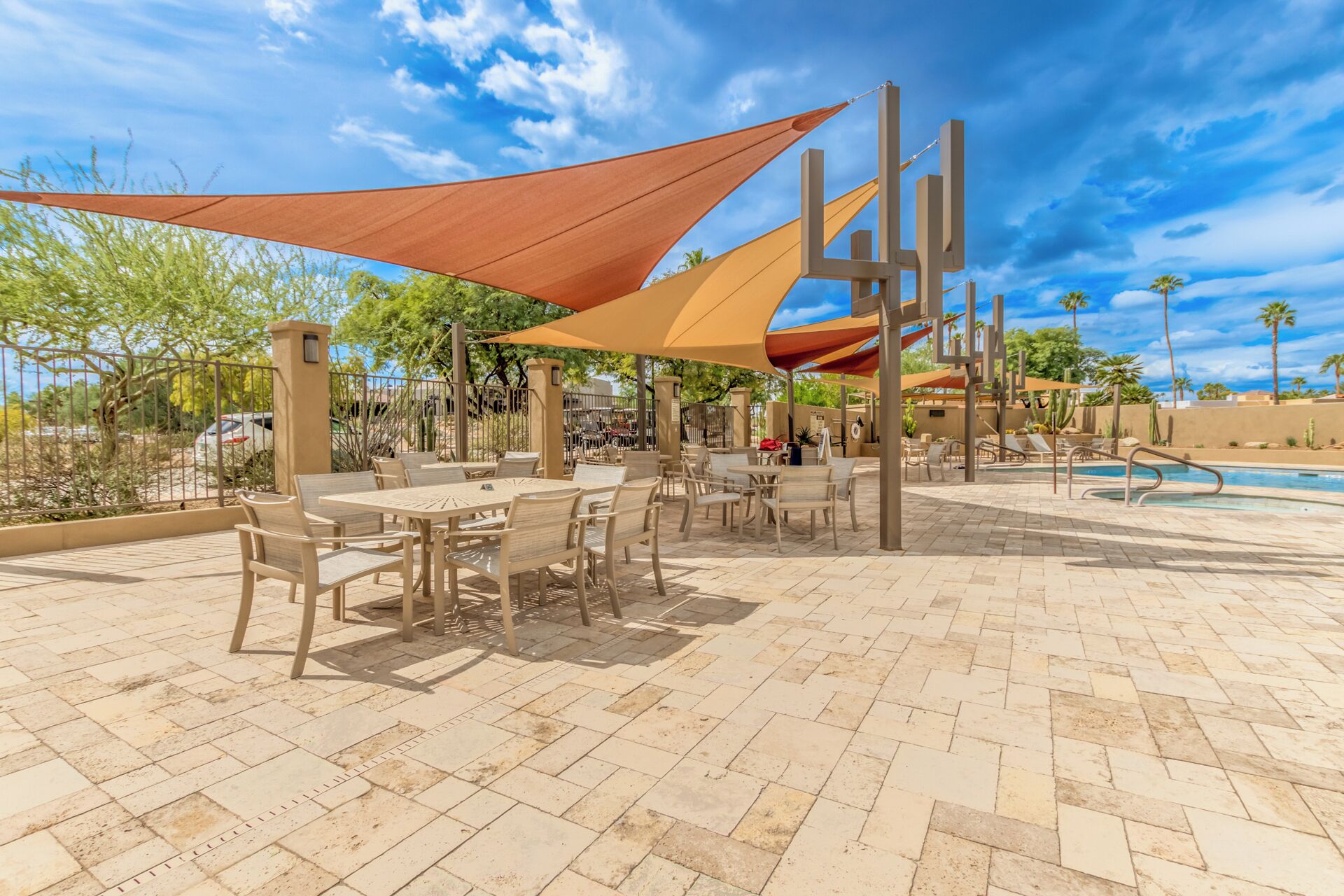 An outdoor patio area with tables and chairs, a pool, and a desert landscape in the background.