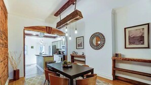 Un comedor con una mesa de madera, cuatro sillas y lámparas colgantes.