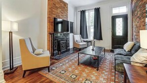 Una sala de estar con chimenea, un sofá, una mesa de centro y un televisor.