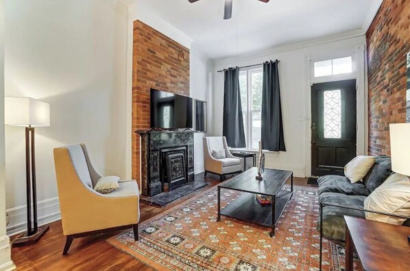 Una sala de estar con chimenea, un sofá, una mesa de centro y un televisor.
