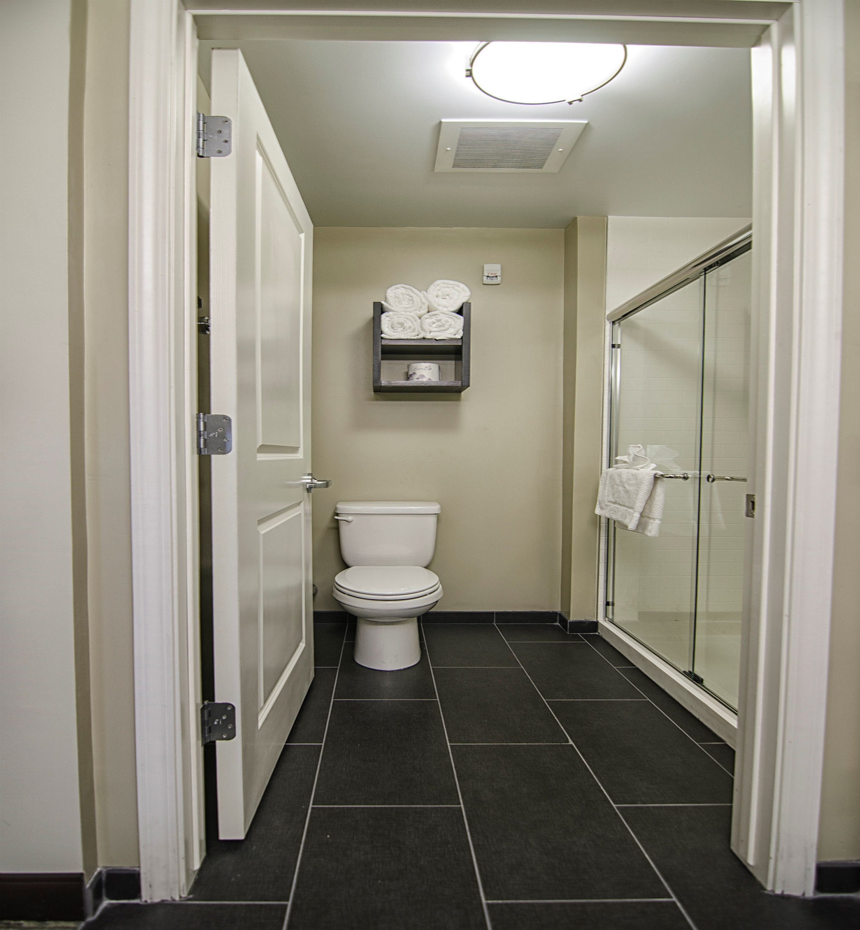 A bathroom with a toilet, a towel rack, and a glass shower enclosure.