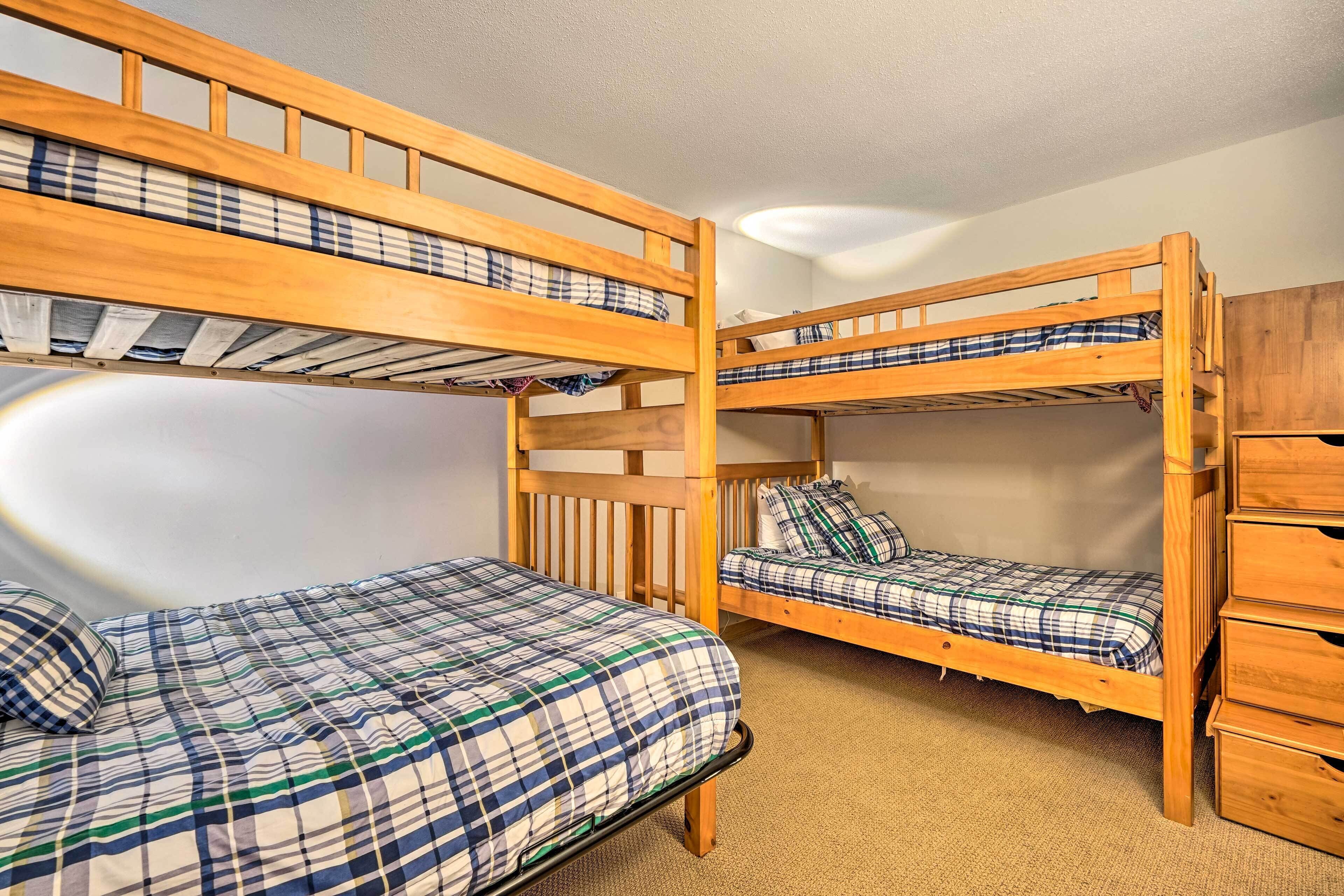 Dormitorio con literas, cabecera de madera, una cama individual con cubrecama a cuadros y un armario de madera.