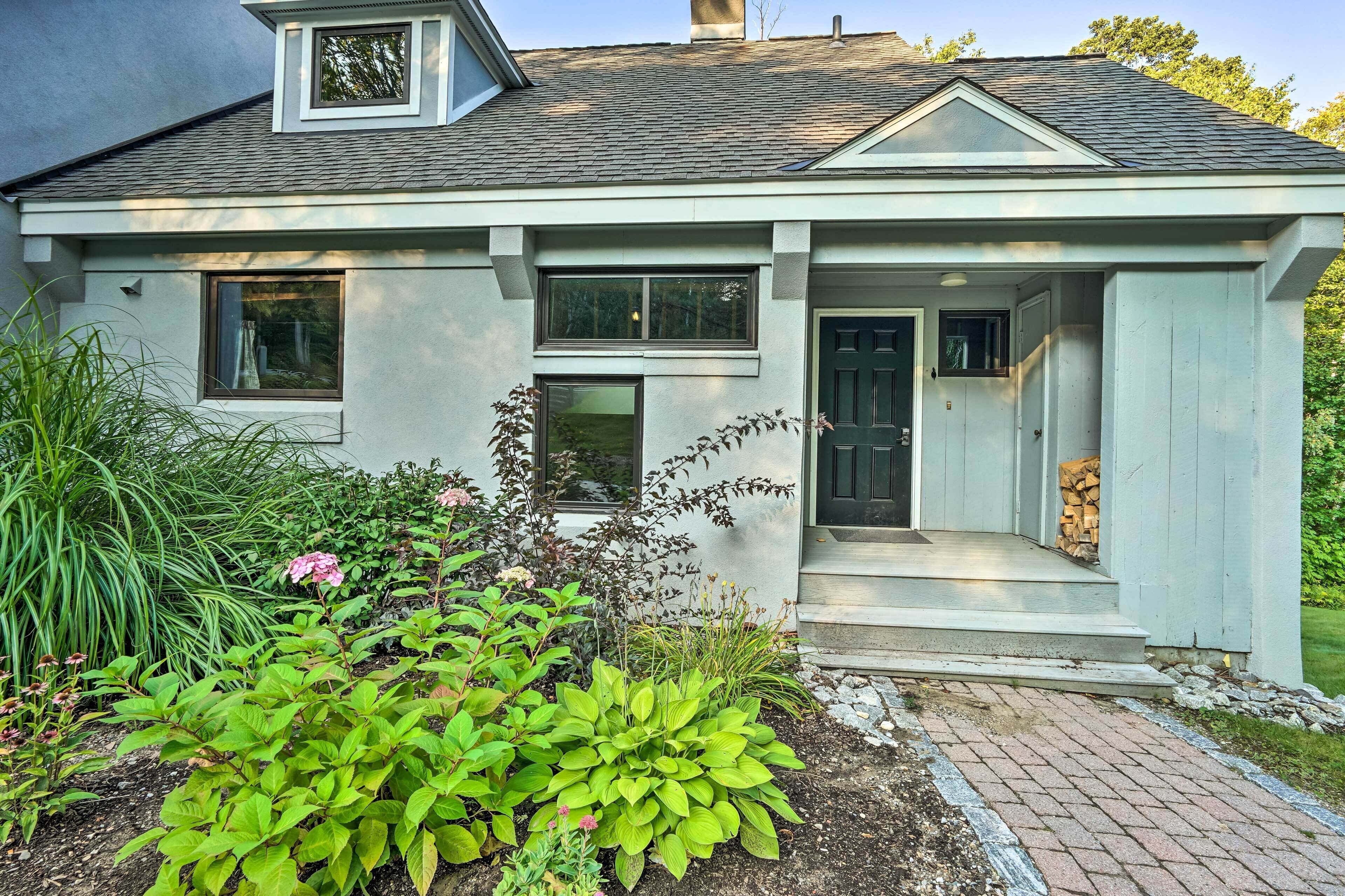 A house with a front porch, a garage, and a landscaped garden with various plants and flowers.