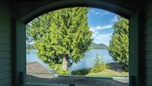 A window with a view of a lake, trees, and a distant mountain. - Bears Beach House (Tofino)