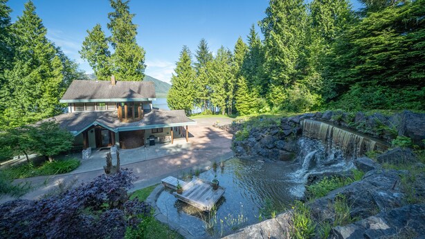 A lodge with a pond, surrounded by dense forest and a waterfall. - Bears Beach House (Tofino)