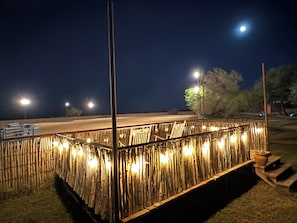 Un espacio al aire libre de noche con valla de bambú, farolas y vista despejada de la calle.