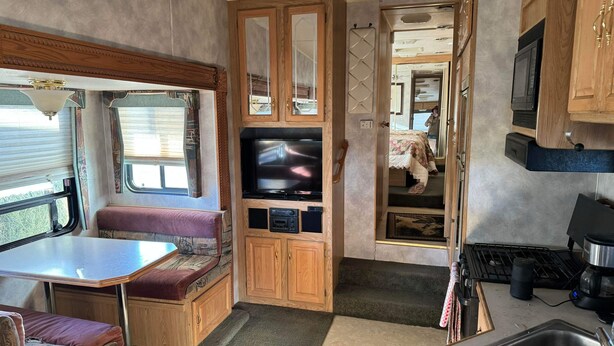 Ein kompaktes Wohnmobil-Interieur mit Küchenzeile, einer Sitzecke und einem Fernseher.