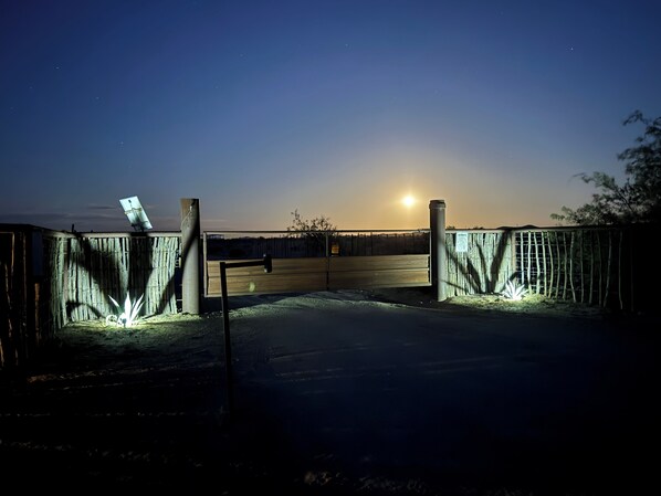 A gated area with a wooden fence, a metal gate, and a solar panel. - Wickenburg Arizona 5th wheel (Wickenburg)