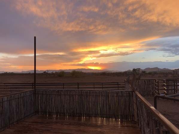 A wooden deck with a metal railing, overlooking a desert landscape with distant mountains and a sunset. - Wickenburg Arizona 5th wheel (Wickenburg)