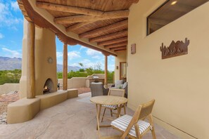 An outdoor patio with a stone floor, wooden furniture, a fire pit, and a view of mountains. - Bellas Catalina Oasis - Private Pool and Magnificent Mountain Views (Tucson)
