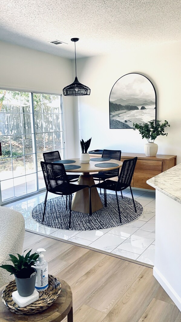 A modern dining area with a round table, black chairs, and a black pendant light. - Beautiful home in the Heart of Five Forks, Simpsonville! (Simpsonville)