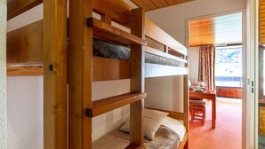 Une chambre avec des lits superposés, un plafond en bois et une vue sur l’extérieur par une fenêtre.