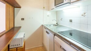Une cuisine compacte avec des carreaux blancs, un four à micro-ondes, un évier et un lave-vaisselle.