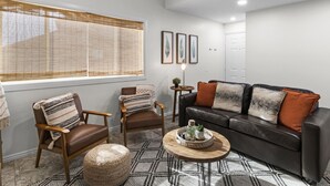 A living room with a brown leather sofa, two wooden chairs, a coffee table, and a patterned rug. - Updated condo with pools near golf courses (St. George)