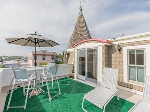 A rooftop terrace with outdoor furniture, a conical roof, and a view of surrounding buildings. - Jackson St. Penthouse Condo. Middle of Downtown. (Cape May)