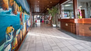 Un couloir avec une fresque murale sur le côté gauche, un plafond en bois et un comptoir d’accueil sur le côté droit.