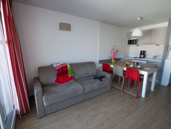 Un espace de vie compact comprenant un canapé, une table à manger et un coin cuisine.