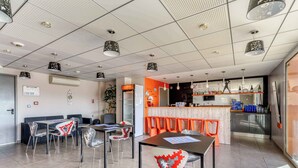 A modern hotel lobby with a seating area, a bar, and a reception desk. - Piscine sur place ! Appart avec Climatisation (Latour-Bas-Elne)