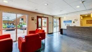 A reception area with a reception desk, a clock, and a window with a view of the outside. - Appart Cozy Près des Pistes! | Sauna Sur-Place (La Féclaz)