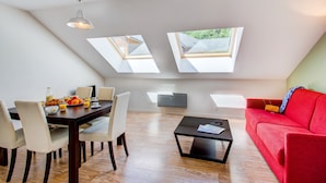 A modern living room with a dining area, skylights, a red sofa, and a coffee table. - Appart Cozy Près des Pistes! | Sauna Sur-Place (La Féclaz)