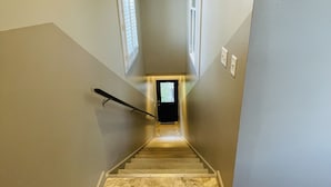 Una escalera estrecha con barandilla que lleva a una puerta en la parte superior.