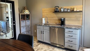 Una cocina moderna con un refrigerador de acero inoxidable, una cafetera y un protector contra salpicaduras de madera.