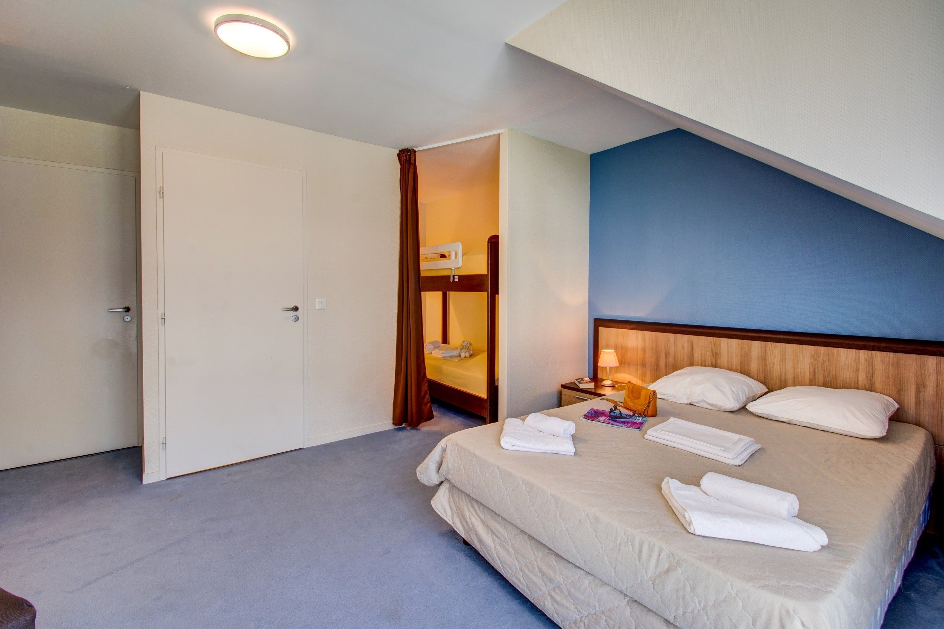 Ein Hotelzimmer mit Bett, Nachttisch, Lampe und Kleiderschrank.