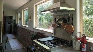 Una cucina moderna con piano cottura a gas, pentole appese e un estintore.