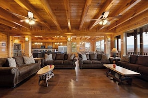 A log cabin interior with wooden walls, ceiling fans, a dining area, and a kitchen.