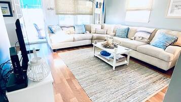 Relax in this inviting living space with a comfortable sofa, coffee table, and large window offering a view of the outdoors.