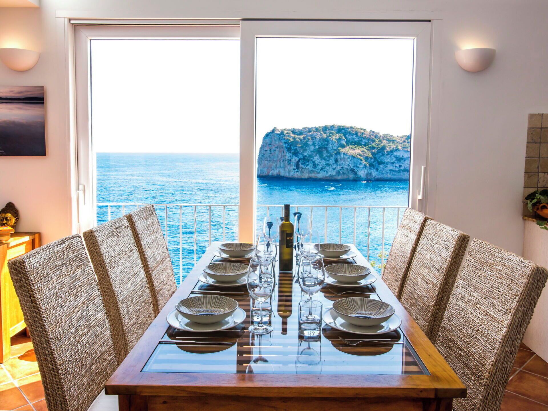 Une table à manger dressée pour six personnes, avec vue sur la mer et les falaises.