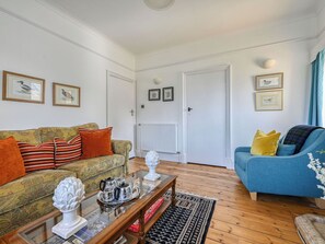 A living room with a sofa, a coffee table with decorative items, and a blue armchair.