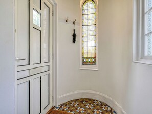 Un pasillo con una puerta blanca, un vitral y un suelo estampado.