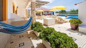 Un espace aménagé au bord de la piscine, avec des chaises longues, un hamac et des parasols.