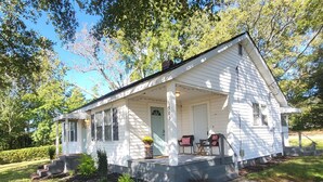 A white single-story house with a porch, a small garden, and a mailbox. - Classy Copacetic Cottage-King bd, Clean, close to Downtown, Furman, Swamp Rabbit (Greenville)