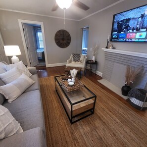 Ein Wohnzimmer mit Sofa, Couchtisch, Fernseher, Kamin und einer Wanduhr.