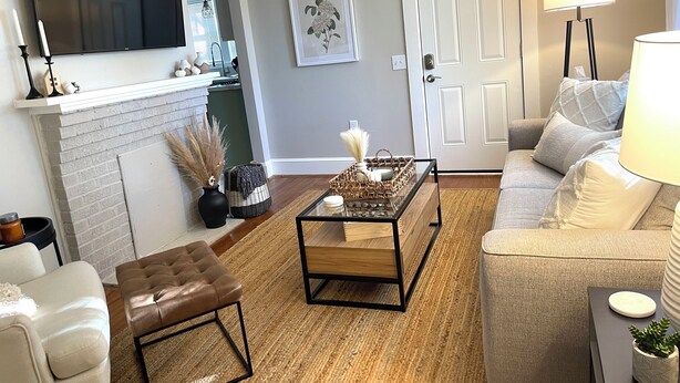 A living room with a fireplace, a television, a sofa, a coffee table, and a lamp. - Classy Copacetic Cottage-King bd, Clean, close to Downtown, Furman, Swamp Rabbit (Greenville)